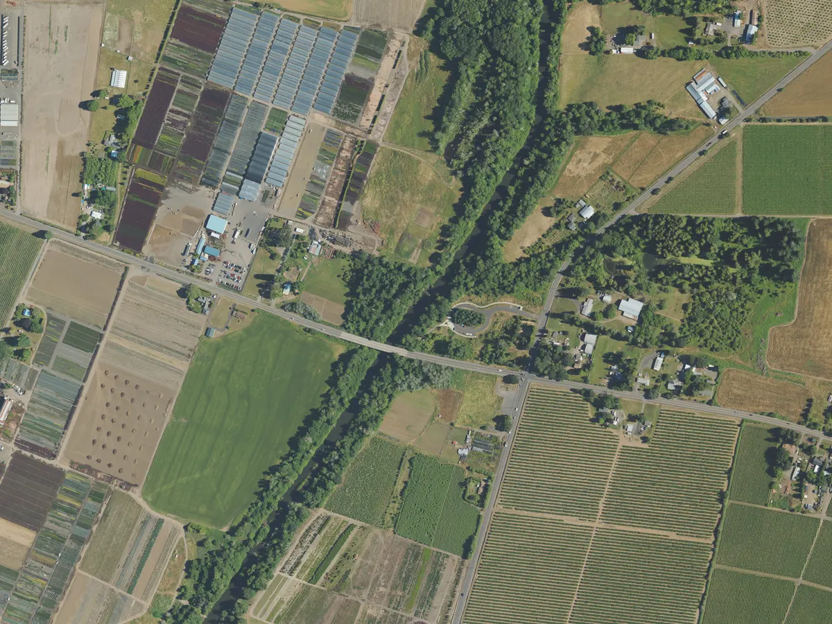 Aerial picture of farmland along a river, with a digital overlay outlining an orchard, a pasture, greenhouses, the river corridor and buildings